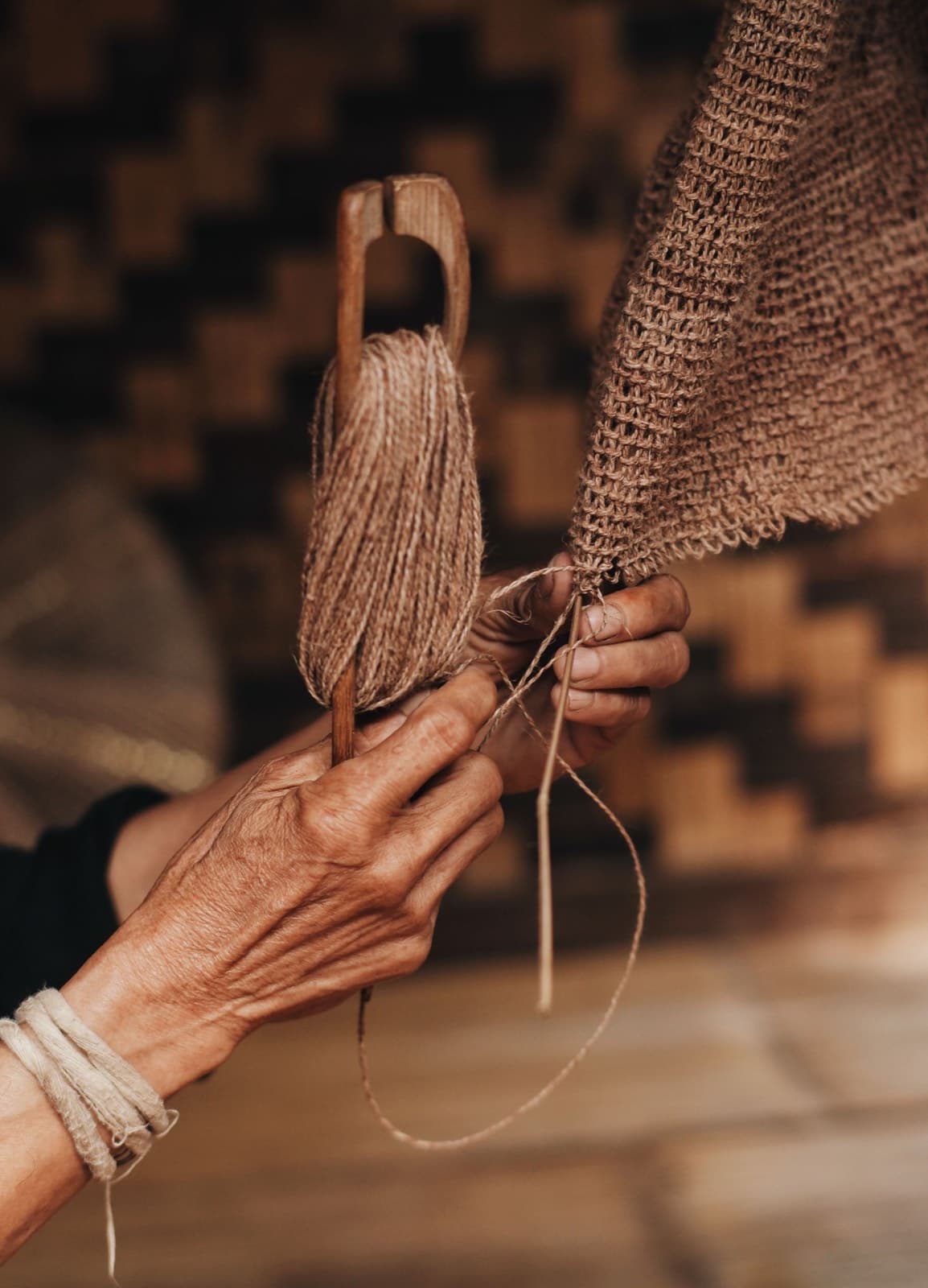 A weaver's hands winding spun yarn onto a wooden spindle